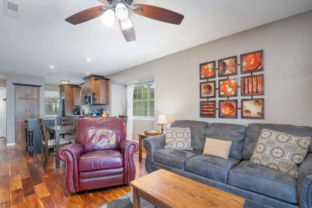 A welcoming family area with a red leather armchair, grey sofa, and wooden coffee table. Stylish decorative wall art enhances the cozy vibe, creating a space ideal for group games, conversations, or movie nights.