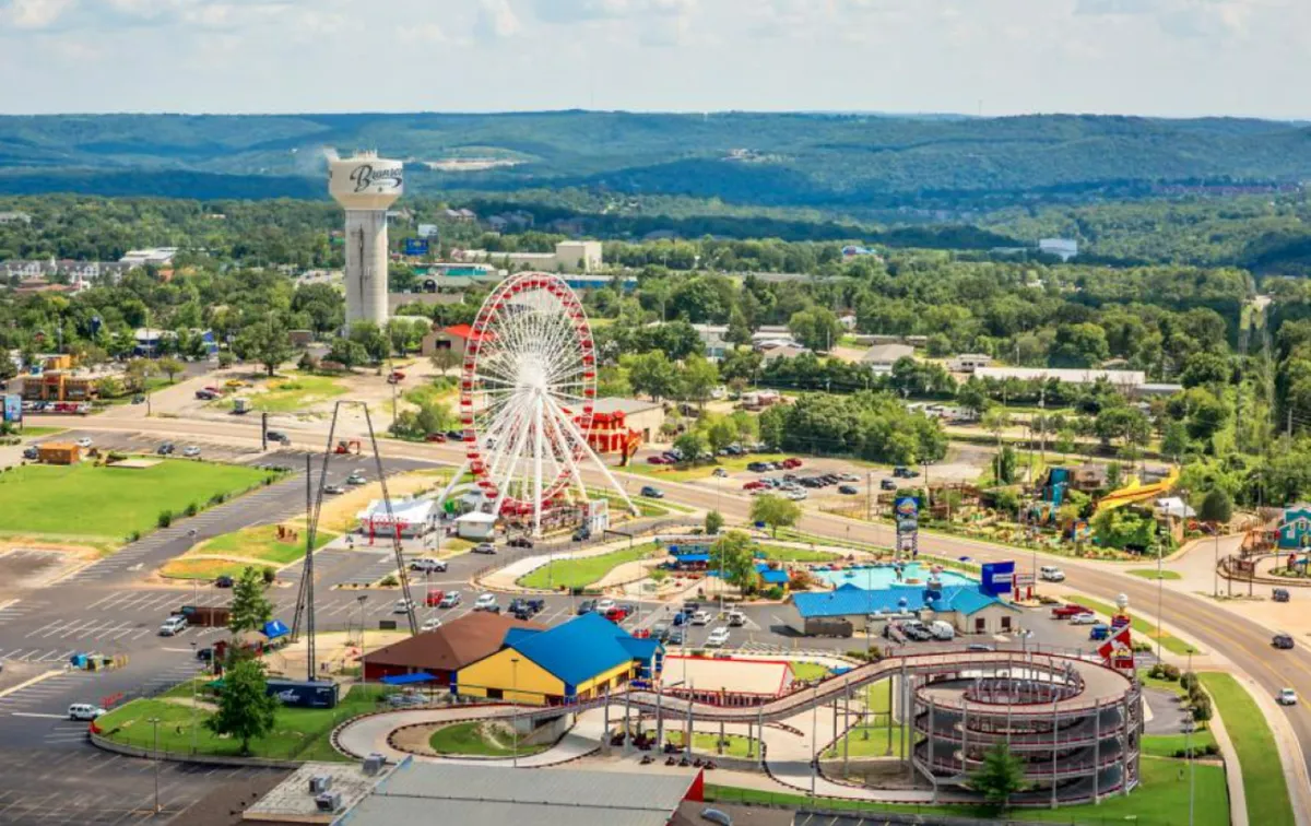 This image captures the lively atmosphere of an amusement park with a ferris wheel, roller coaster, colorful buildings, and a water tower. The vibrant scene is bustling with activity and energy, perfectly reflecting the joy and excitement of a family outing at Silver Dollar City.