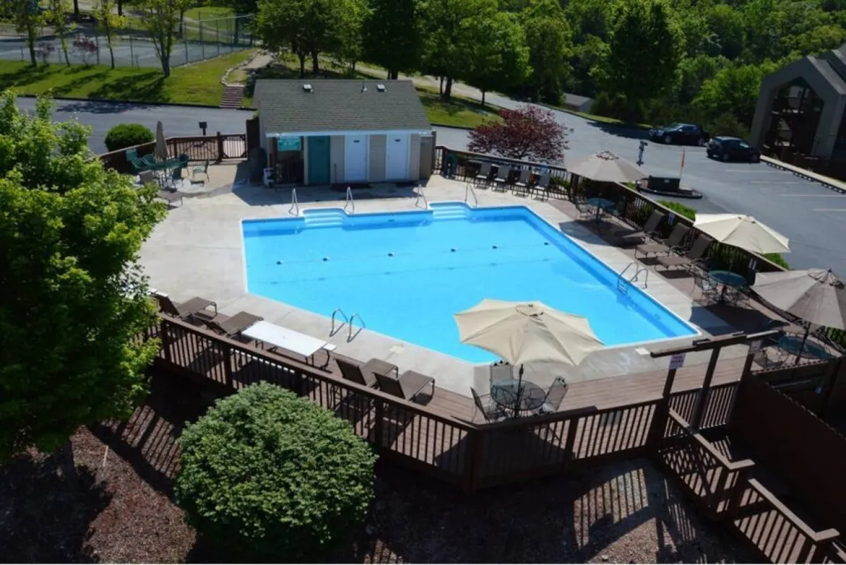 A sparkling swimming pool with deck chairs and umbrellas is set next to a charming pool house. The scene exudes a sense of relaxation and sociability, ideal for gatherings with family and friends or quiet afternoon lounging.